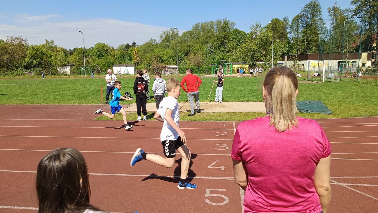 uczniowie uprawiający lekką atletykę na boisku szkolnym